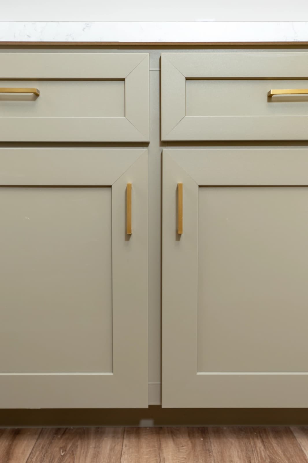 Sage-green kitchen cabinets with brushed-gold bar pulls.