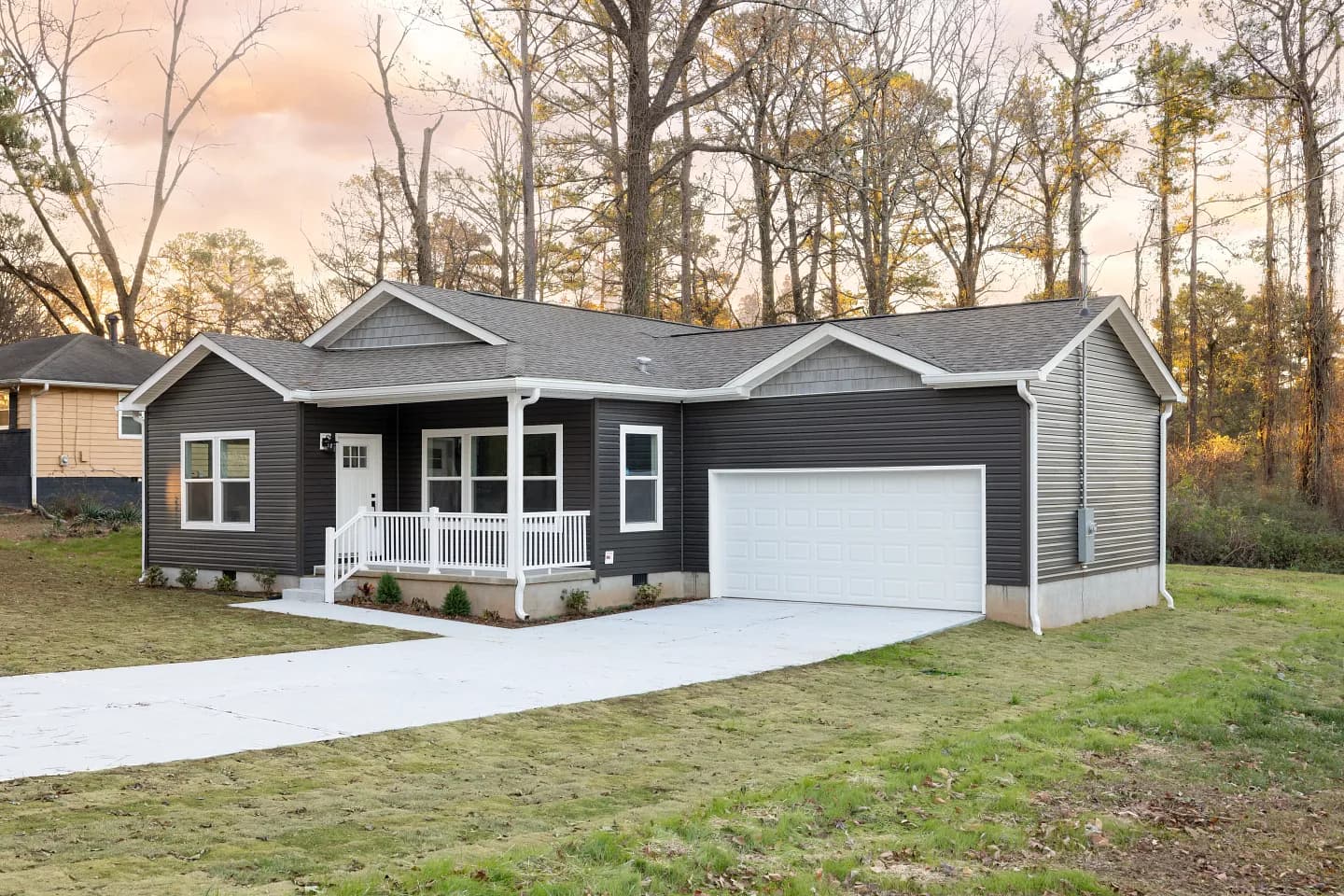 New construction modern manufactured home exterior with grey siding and white trim on private land.