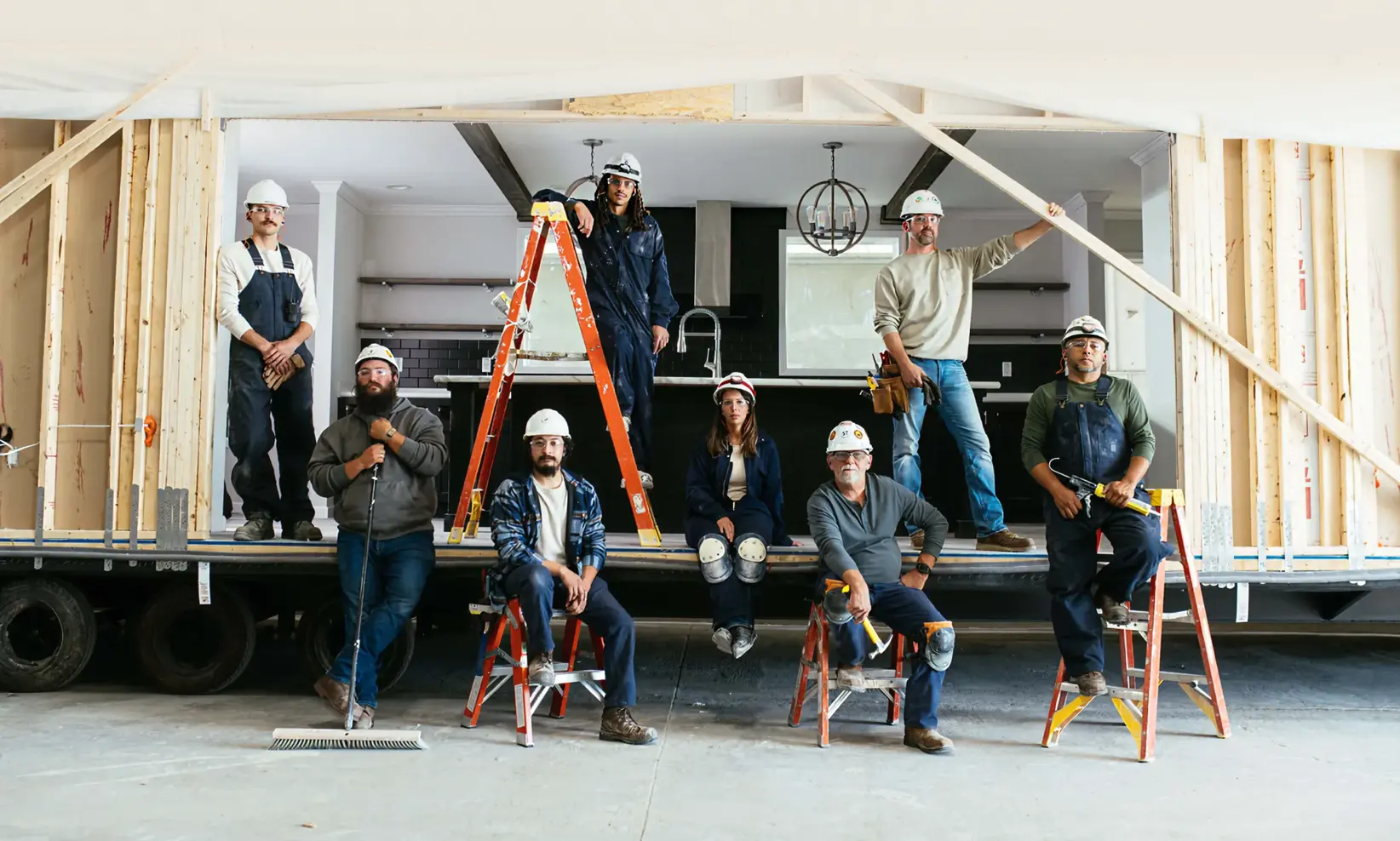 Home building and construction crew members next to a modern manufactured home by Clayton.