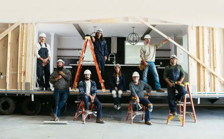 Home building and construction crew members next to a modern manufactured home by Clayton.